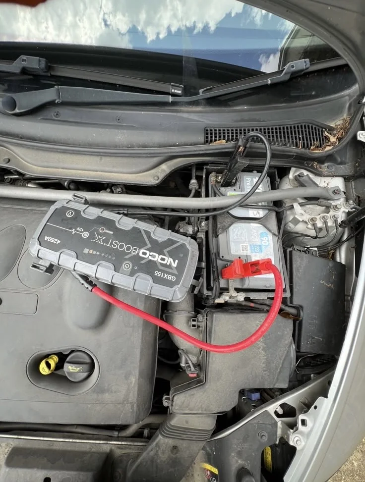 NOCO jump pack clamped to a car battery starting a flat vehicle